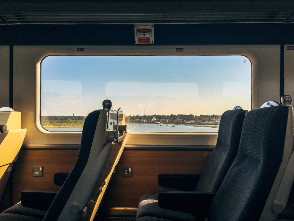 Side view of empty passenger seats in a modern train carriage interior with scenic coastal view